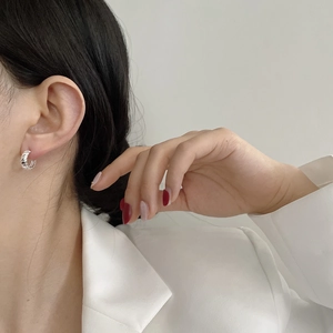 Gros plan de boucles d'oreilles créoles torsadées en argent S925 portées par un mannequin