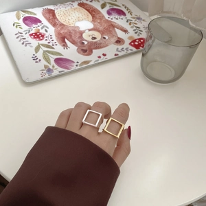 Nahaufnahme von minimalistischen, hohlen, quadratischen Ringen in Gold und Silber