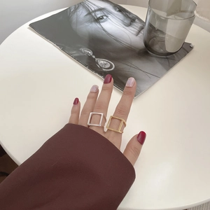 Detail von minimalistischen hohlen quadratischen Ringen in Gold und Silber am Finger