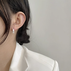 Gros plan d'une créole argentée à texture torsadée portée par un mannequin en style chic