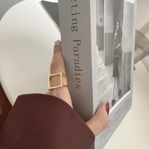 Nahaufnahme eines minimalistischen, hohlen quadratischen Goldrings am Zeigefinger