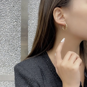 Detail of irregular textured gold C-shape stud earrings on model with hammered finish