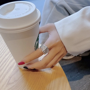 Close-up of a wide silver ring with rock texture worn while holding a coffee cup