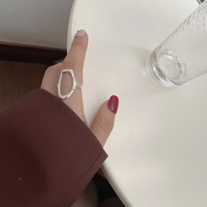 Detail of s925 sterling silver hollow oval ring worn on finger in minimalist style