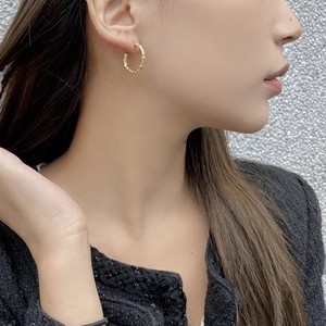 Modern gold C-shape hoop earrings with irregular hammered texture on female model