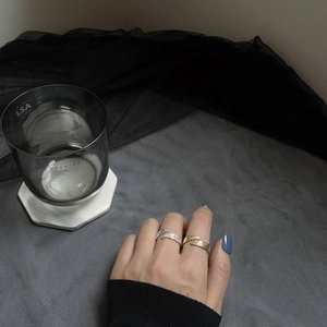 Detailed view of adjustable silver and gold open rings with textured feather pattern