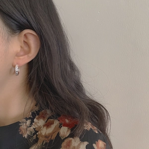 Detail of C-shaped 925 silver earrings with Greek pattern on a female model