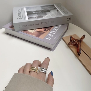 Detail of gold and silver irregular wavy textured wide rings worn on fingers