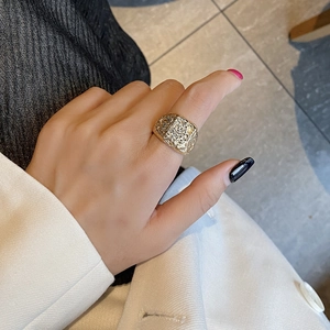 Retro golden square ring with textured surface on a model wearing white suit