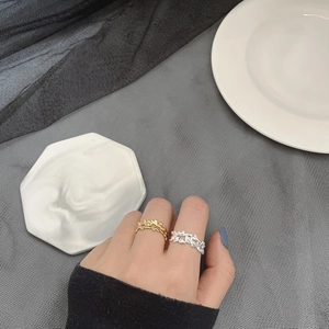 Close-up of gold and silver irregular wave texture rings worn on finger with artistic design