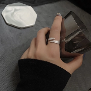 Close-up of a silver irregular foil texture ring worn on a finger holding a black glass