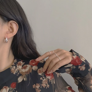 Detail of 925 silver C-shape earrings with hammered texture and glitter rings on model