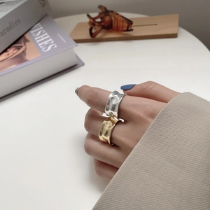 Detail of stacked irregular hammered silver and gold wide rings on a finger