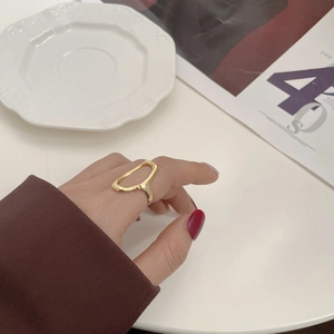 Detail of a minimalist gold hollow oval geometric ring worn on model finger