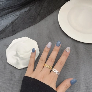 Macro detail of gold and silver irregular wave texture rings on hand with a sleek finish