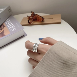 Close-up of a wide 925 sterling silver ring with an irregular wavy surface texture