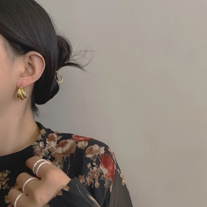 Gros plan de boucles d'oreilles créoles dorées à trois couches portées par un mannequin