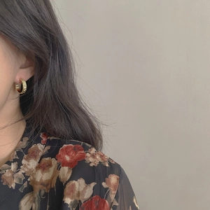 Detailed view of vintage gold C-shape hammered earrings worn on a model's ear