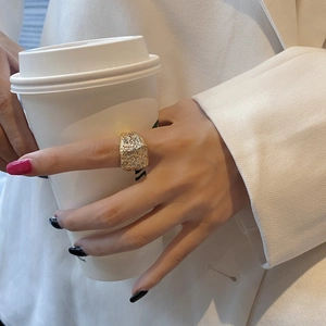 Detailed close-up of a wide golden textured ring featuring a unique hammered pattern