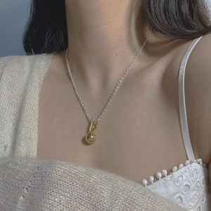 Detail of S925 silver OT buckle necklace with polished gold bead pendant on a model