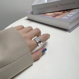 Macro shot of silver irregular wavy ring showing textured hammered finish on index finger