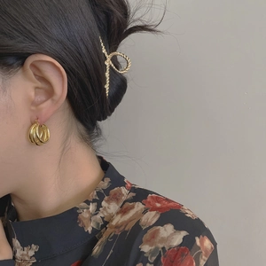 Détail des boucles d'oreilles créoles dorées portées par un mannequin en tenue rétro