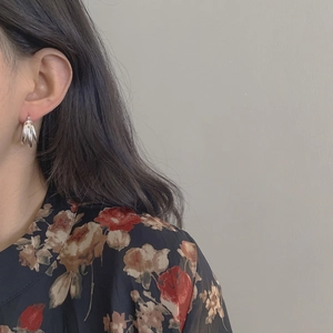 Gros plan de boucles d'oreilles créoles C en argent massif S925 portées par un mannequin