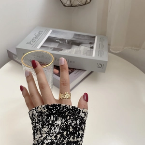 Detail of wide gold irregular lava texture ring worn on finger in elegant lifestyle setting