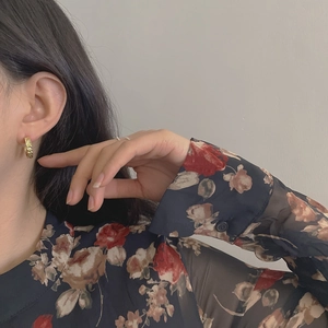 Detailed view of a gold chain-textured C-shaped earring on a model ear
