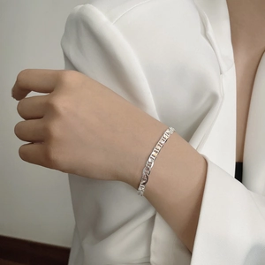 Polished 925 sterling silver pig nose link chain bracelet worn with a stylish white suit