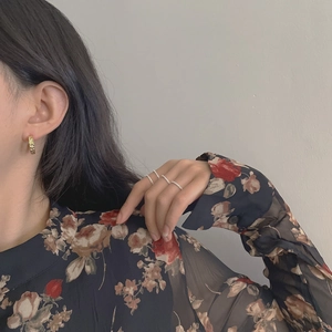 Close-up of vintage C-shaped gold textured earring and sparkling rhinestone rings on a model