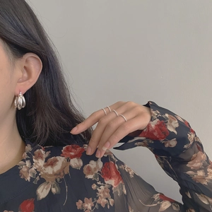 Détail de boucles d'oreilles triple créoles en argent et bagues portées par un mannequin