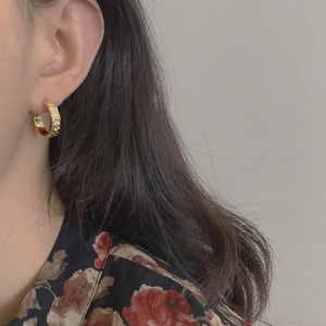 Vintage gold-plated C-shaped earrings with hammered texture worn by a female model