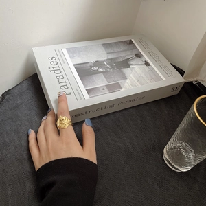 Dettaglio di un anello dorato irregolare sulla mano con sfondo di libro elegante