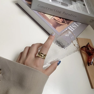 Detailed view of an irregular textured golden wide ring with polished metallic finish