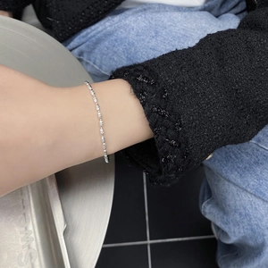 Macro detail of a 925 sterling silver beaded bracelet on a woman's wrist with a tray