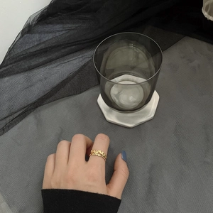 Close-up of golden double heart-shaped rings on finger with textured mesh background