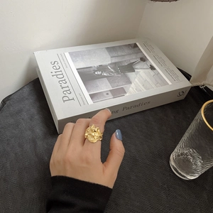 Dettaglio ravvicinato di un anello dorato irregolare stile lava su mano con sfondo minimalista