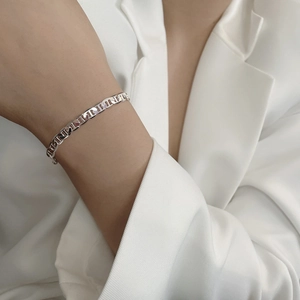 Detail of 925 sterling silver mariner link bracelet worn over a white suit sleeve