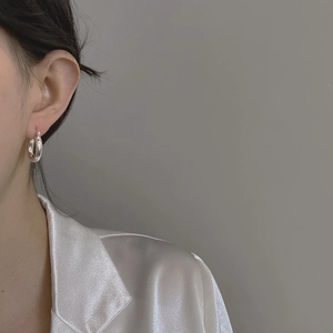 Macro close-up of a minimalist polished S925 sterling silver hoop earring worn by a model