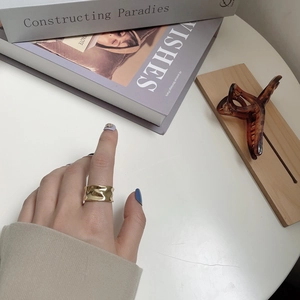 Macro detail of wide gold ring with irregular hammered texture on person finger