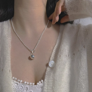 Detail of S925 sterling silver necklace with round bead pendant and toggle clasp on neck