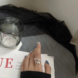 Vue détaillée d'une bague en argent en forme de branche portée sur la main avec VOGUE