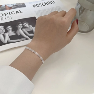 Detailed view of silver multi-row bead bracelet with woven texture on a fashion magazine