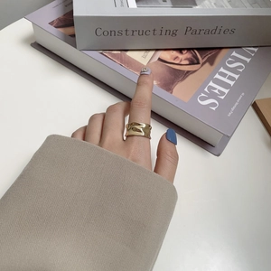 Detail of a wavy irregular gold ring with hammered texture on the finger