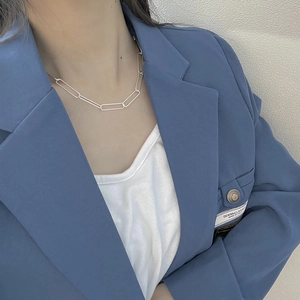 Gros plan d'une chaîne à maillons rectangulaires en argent S925 portée avec un blazer bleu