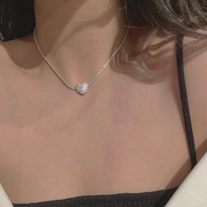 Detail of S925 sterling silver heart necklace with a shimmering crinkled texture on a model
