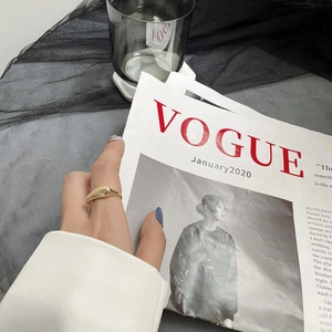 Gros plan d'une bague goutte d'or polie sur la main avec un fond de magazine créatif