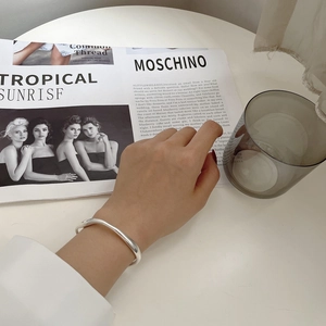 Close-up of minimalist S925 sterling silver open bangle with a polished mirror finish