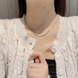 Collier ras du cou perles olive en argent 925 porté par un mannequin en gilet blanc doux